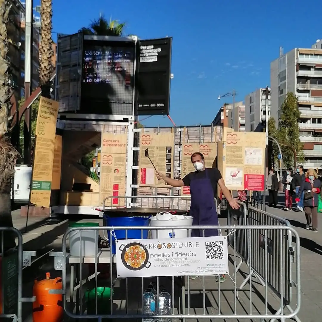 Cua de veïns servint-se paella en una plaça pública durant un esdeveniment local