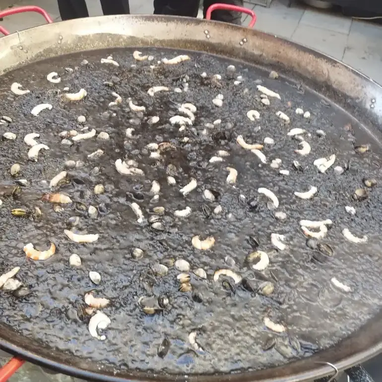Paella d’arròs negre servida amb allioli en una festa privada