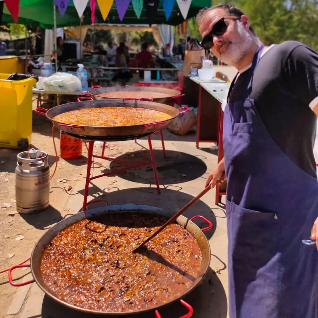 Cocinero preparando una paella gigante para un evento popular al aire libre