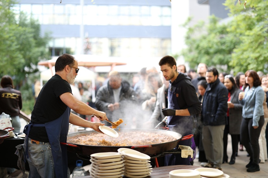 Cuiners servint paella a una cua de convidats