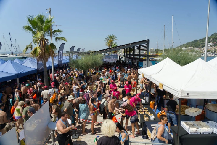 Gent fent cua per la paella en un esdeveniment esportiu al port