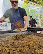 Cuiner servint paella d'una paellera gegant