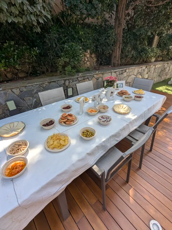 Mesa larga preparada con entrantes en un jardín para una boda