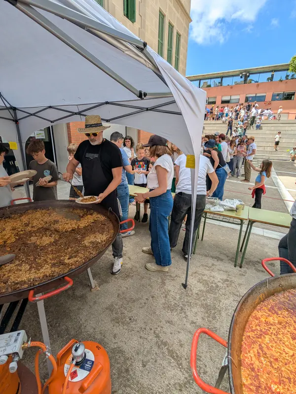 Paelles i cua sota una carpa en una plaça de festa