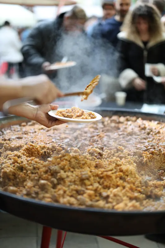 Sirviendo una paella gigante a una cola larga