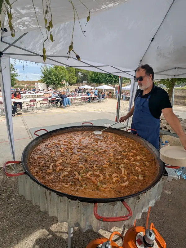 Paella gegant sota una carpa, amb taules al darrere