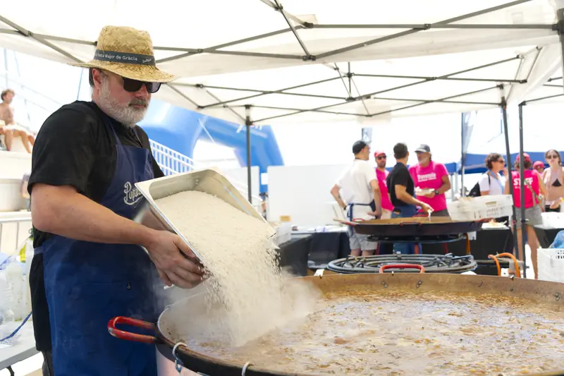 Afegint l'arròs a una paella gegant