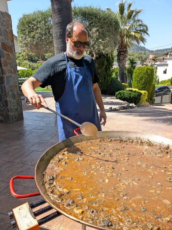 Remenant la paella en un jardí amb palmeres
