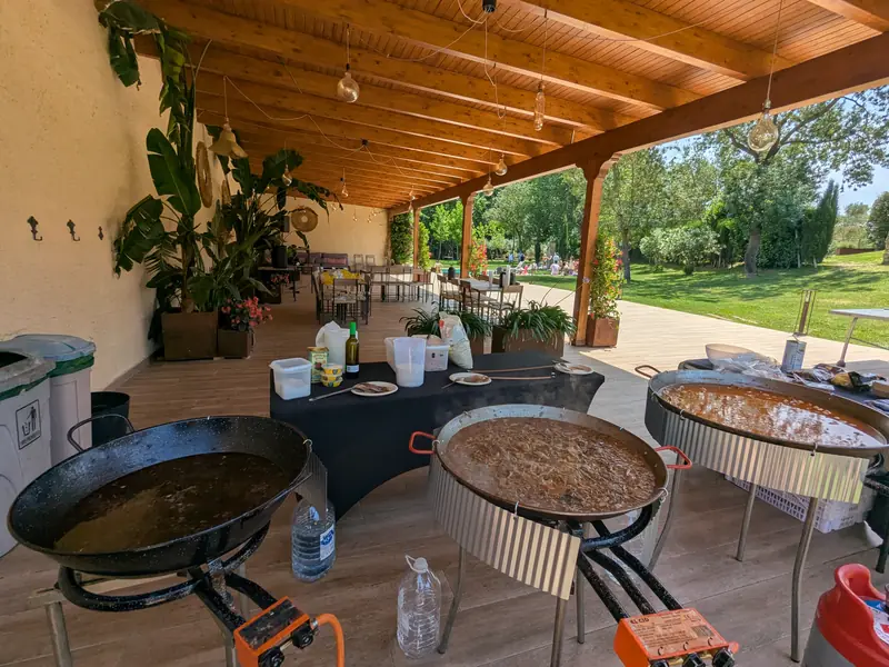 Tres paelles sota un porxo de fusta en una masia