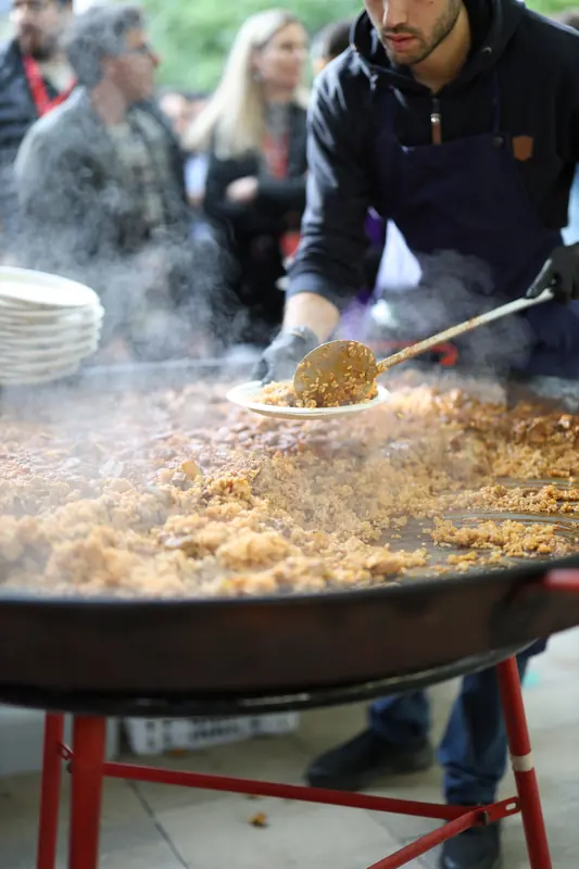 Cuiner servint paella de la paellera