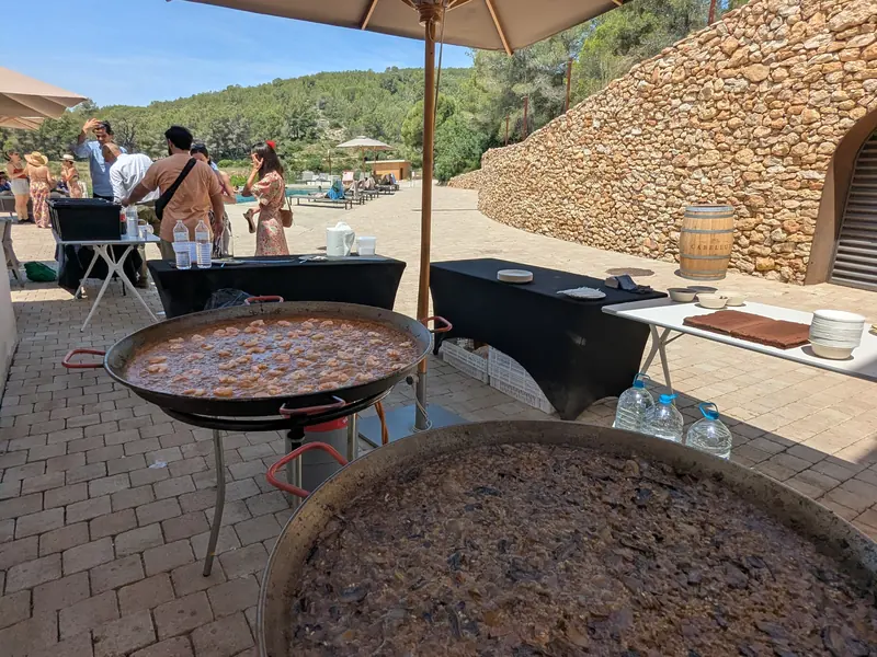 Paelleres cuinant a l'aire lliure al costat d'un mur de pedra